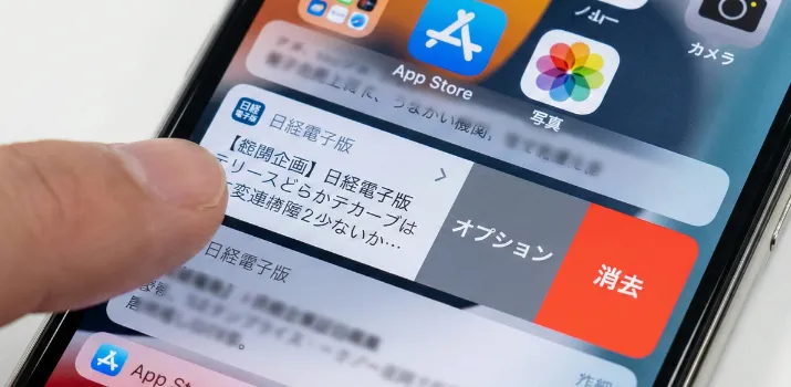 iPhoneの通知センターで、日経電子版の通知を左にスライドし、『オプション』と『消去』ボタンを表示させている操作画面。