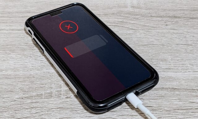 充電ケーブルを挿しても充電されず、画面に赤いバツ印（エラー）と電池切れアイコンが表示されているスマートフォンの様子。